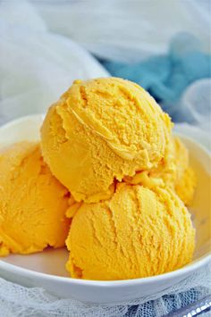 "Creamy mango ice cream scoops in a bowl garnished with fresh mango slices."