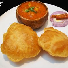 "A plate of golden, crispy puris served with spicy aloo (potato) curry garnished with fresh coriander."